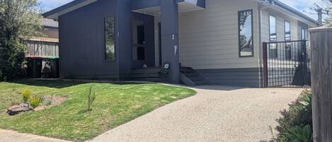 A modern two-story house with a covered porch, a visible number '2' on the side, and a gated driveway.
