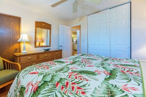 A bedroom with a bed, a dresser, a chair, a lamp, a mirror, and a door leading to another room.