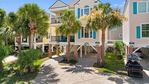 A beachfront hotel with multiple stories, a covered patio, and palm trees. - 6-Bedroom Surfside House with Private Pool and Beach Access (Surfside Beach)