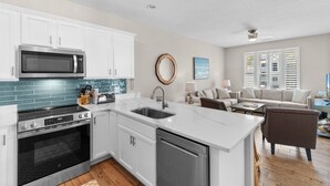 A modern kitchen with white cabinets, a stainless steel microwave, and a dishwasher. - 6-Bedroom Surfside House with Private Pool and Beach Access (Surfside Beach)