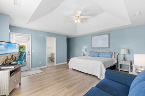 A bedroom with a bed, two bedside tables, a ceiling fan, a door leading to a balcony, and a view of the beach. - 6-Bedroom Surfside House with Private Pool and Beach Access (Surfside Beach)