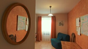 Um quarto com piso de madeira, um sofá azul, uma mesa de madeira e um espelho na parede.