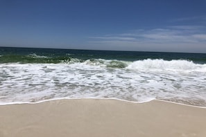Uma praia com ondas quebrando na costa sob um céu claro.