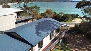 A two-story building with a flat roof, a balcony, and a view of a large body of water and distant mountains. - Front Row Beachfront (Binalong Bay)