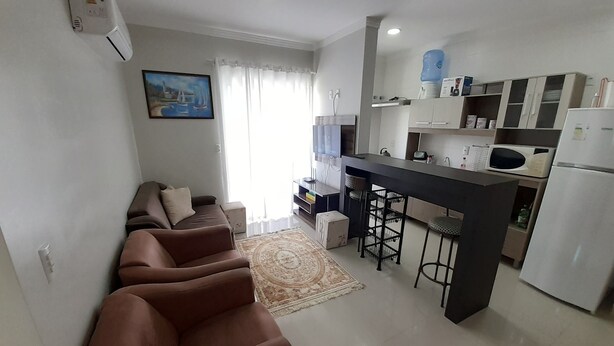 Un appartement moderne comprenant un salon avec un canapé, une cuisine avec un bar et un coin repas.