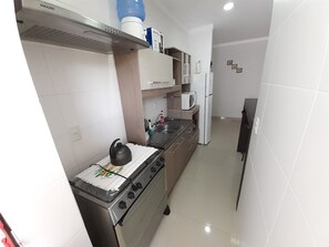 A compact kitchen with a gas stove, microwave, and refrigerator.