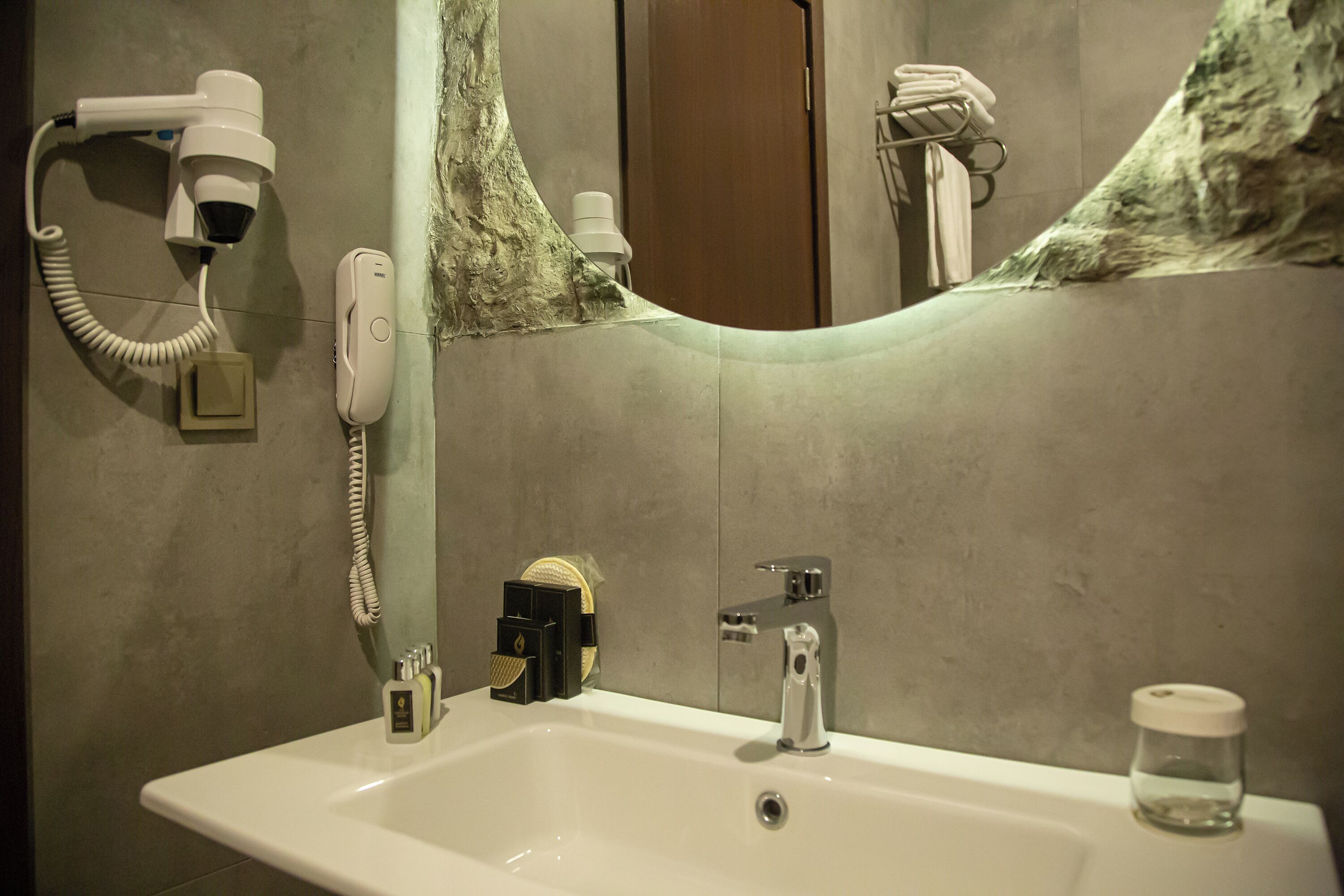 Un baño con lavamanos, espejo, secador de pelo y toallero.