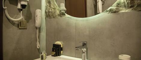 Un baño con lavamanos, espejo, secador de pelo y toallero.
