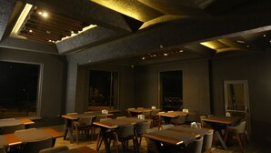 A dimly lit restaurant with tables and chairs arranged for dining. - The Erzurum Hotel (Erzurum)