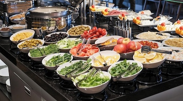 A buffet with various food items including fruits, vegetables, and salads.