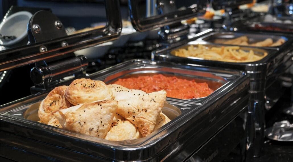 A buffet with various food items including pastries and a red sauce.