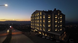 A multi-story hotel with a modern design, featuring a row of uniformly lit windows and a flat roof.