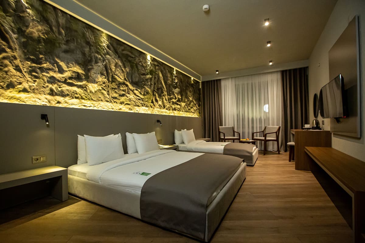 Een hotelkamer met twee bedden, een bureau, een stoel, een televisie en een wand met een structuurpatroon.
