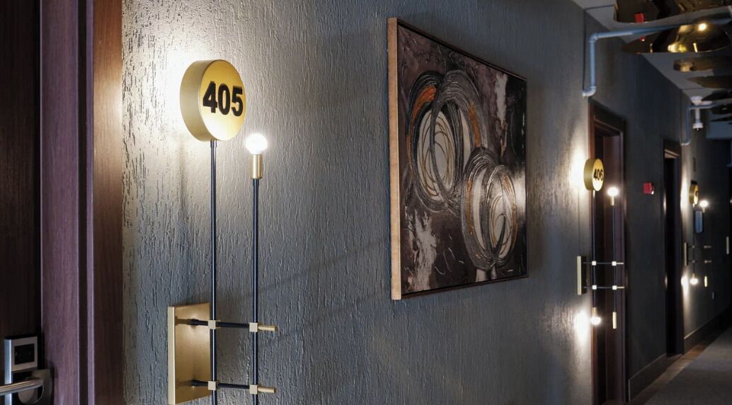 A hallway with a number sign '405', a modern light fixture, and a framed abstract painting on the wall.
