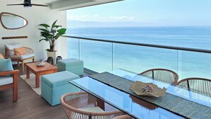 A balcony with a glass table, wicker chairs, and a view of the ocean. - Beachfront Luxury Condo, Great Location! (Puerto Vallarta)