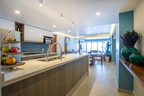 A modern kitchen with a central island, a dining area with a view, and a living space with a large window.