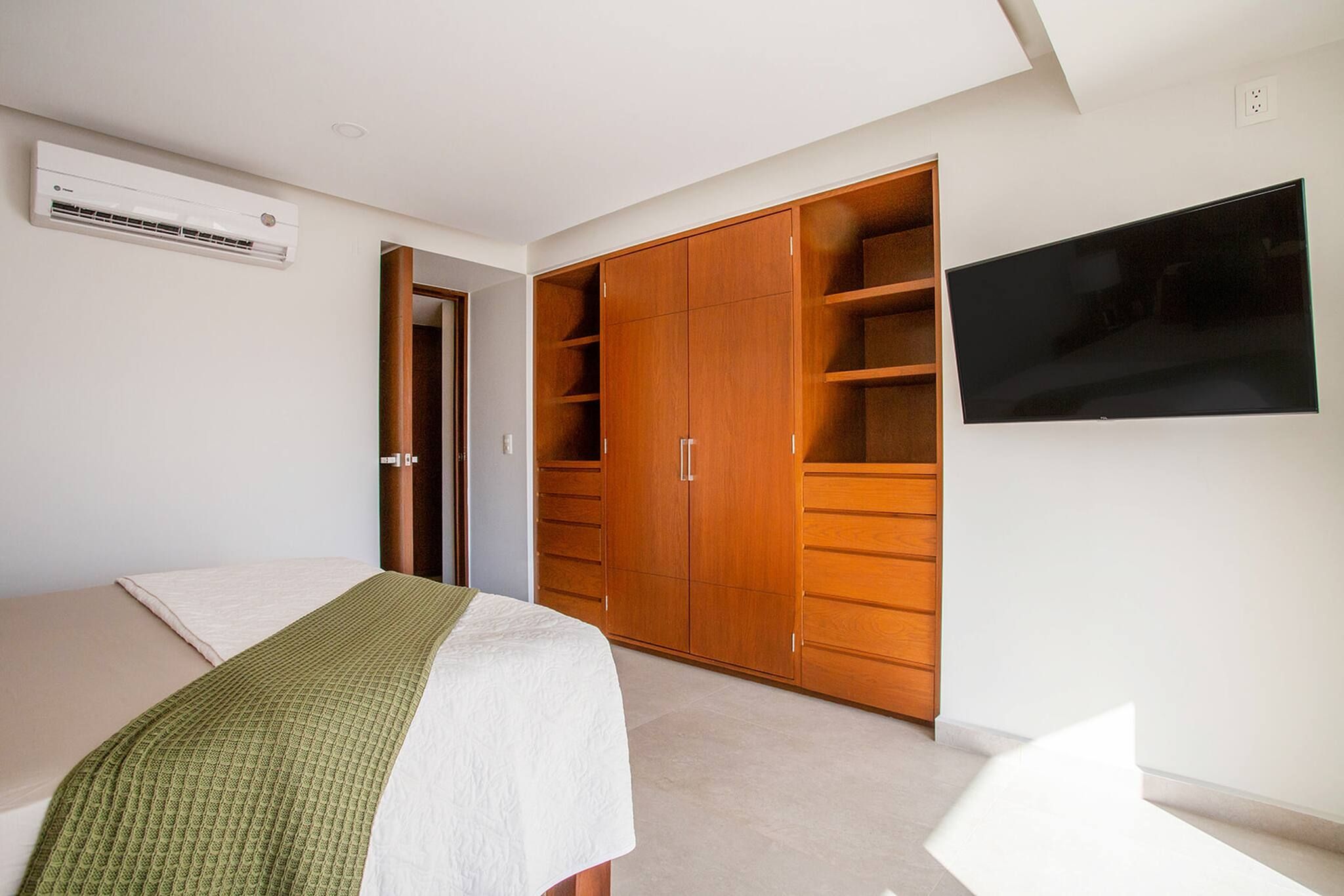 A bedroom with a bed, a wardrobe, and a television.
