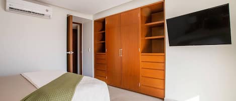 Een slaapkamer met een bed, een kledingkast en een televisie.