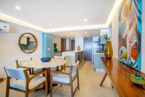 A modern kitchen with a central island, a dining area with a round table and chairs, and a large mirror on the wall.