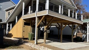 Una casa a due piani con un balcone, un pontile in legno e una zona coperta.