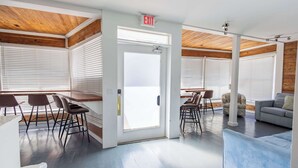 A modern interior with a wooden ceiling, a white door with an exit sign, a blue sofa, and a dining area with chairs. - Commodore's Compound - One block from Duval St (Key West)