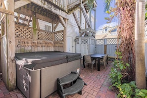 A hot tub with a wooden deck, a table, chairs, and a covered area. - Commodore's Compound - One block from Duval St (Key West)