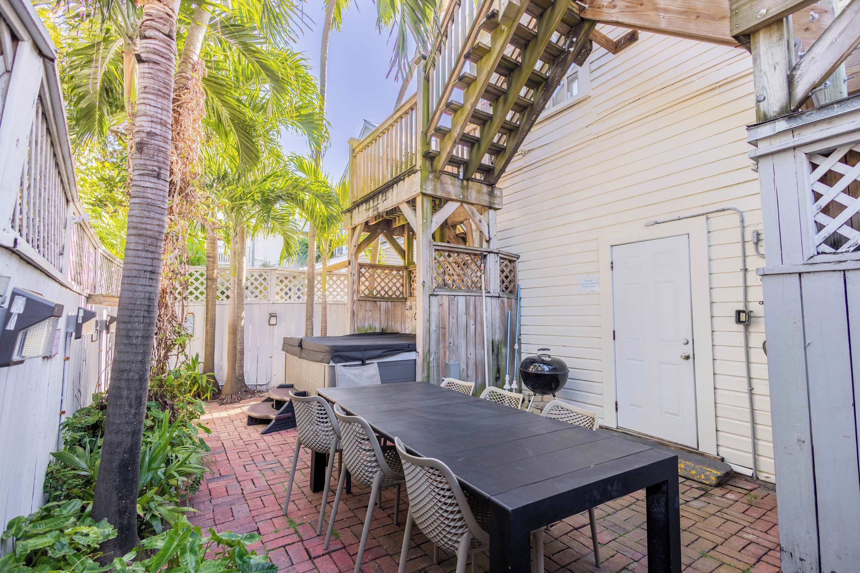 A patio with a table and chairs, a grill, and a wooden deck.