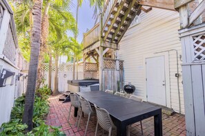 A patio with a table and chairs, a grill, and a wooden deck. - Commodore's Compound - One block from Duval St (Key West)