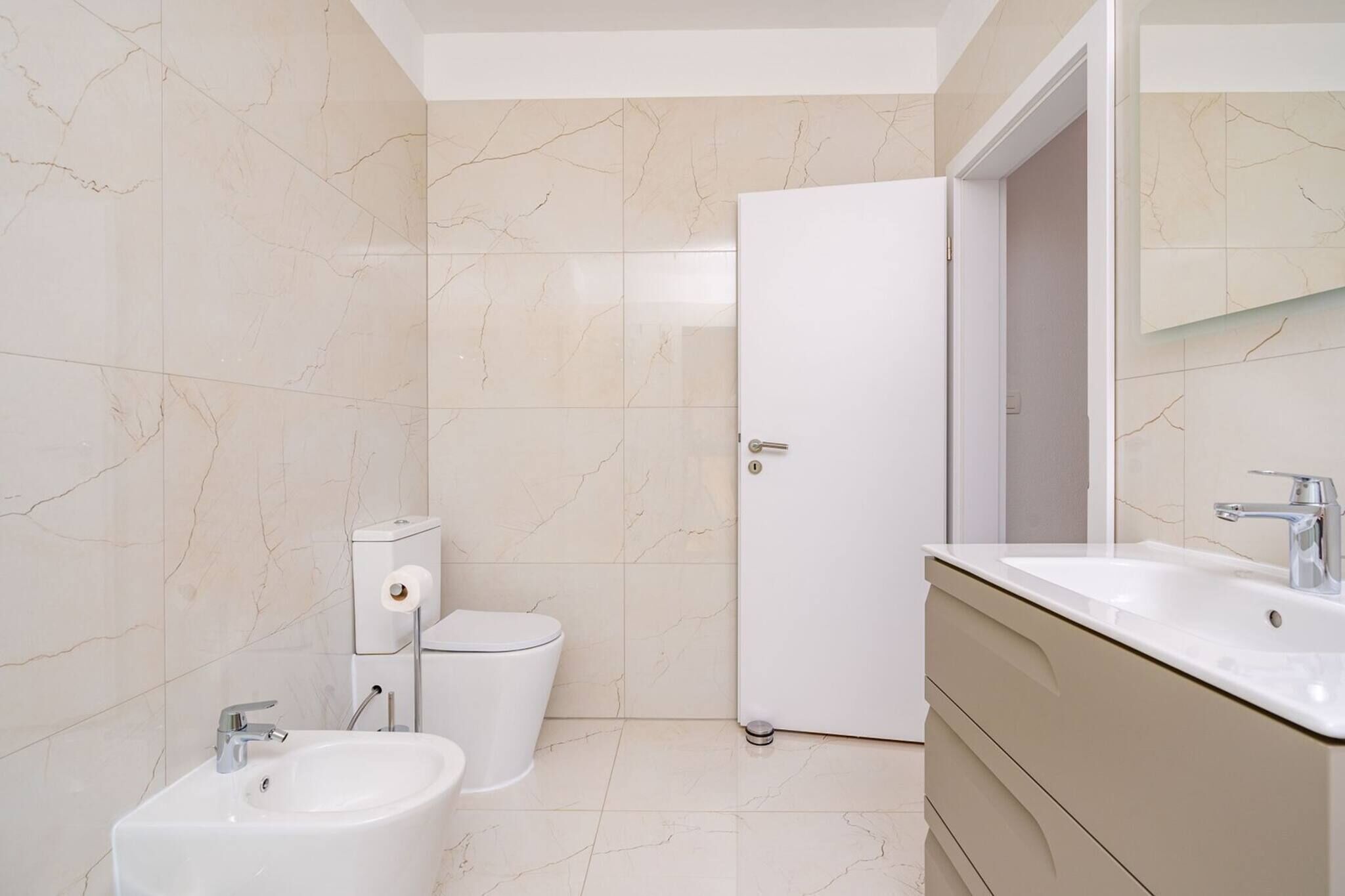 Een badkamer met een hygiëneschuimer, toilet en wastafel.