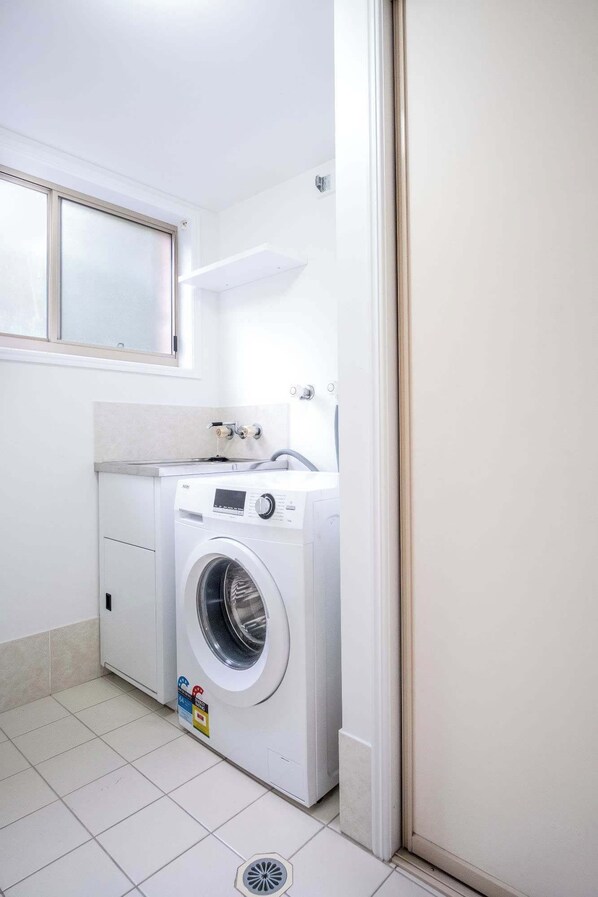 A laundry room with a front-loading washing machine, a dryer, and a tiled floor. - Saltair Kings Beach Apartment - Walk to Beach (Kings Beach)