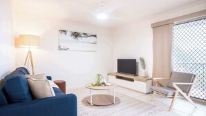 A living room with a sofa, a coffee table, a TV, and a chair. - Saltair Kings Beach Apartment - Walk to Beach (Kings Beach)