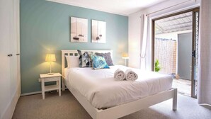 Ein Schlafzimmer mit einem Bett, zwei Nachttischen, einem Deckenventilator und Blick durch eine offene Tür.