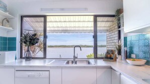 Eine Küche mit einem großen Fenster, einer Spüle und einer Arbeitsplatte mit einer Schüssel und einem Blumentopf.