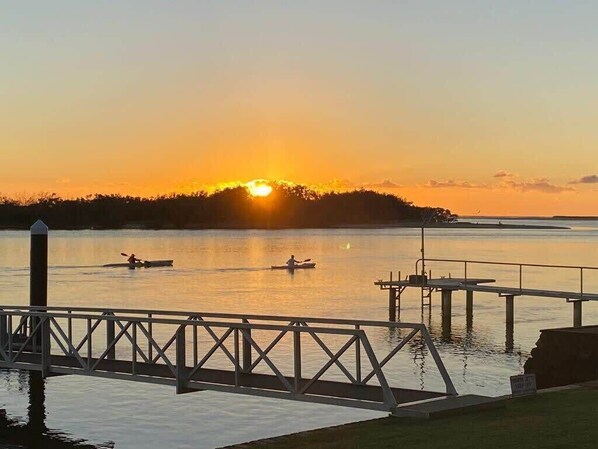 Un atardecer sobre una superficie acuática tranquila, con un muelle y un embarcadero.