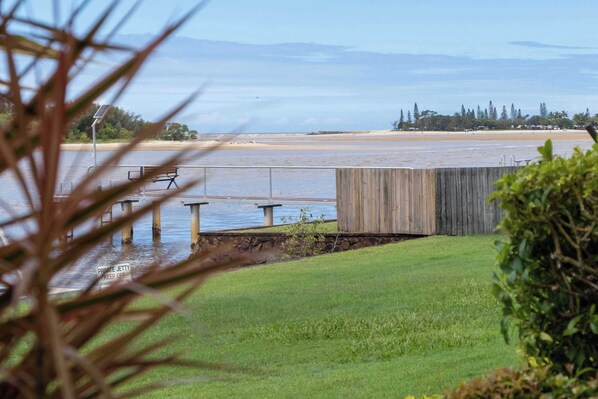 A waterfront property with a wooden dock, a grassy lawn, and a view of the water. - Peaceful River Front Escape Short walk to Ocean St (Maroochydore)