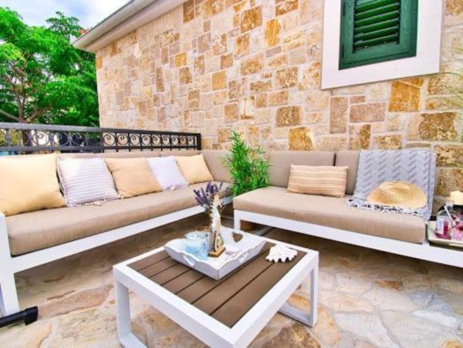 A stone-walled room with a beige sofa, a wooden coffee table, and a decorative plant.