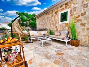A stone-walled room with a sofa, a coffee table, and a hanging chair.