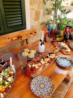 A wooden table set with a variety of food items, including a charcuterie board, a bottle of champagne, and decorative plates.