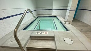 Una piscina amb un cartell de profunditat de 9 metres, una barana metàl·lica i parets revestides de rajola.
