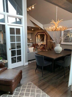A spacious dining area with a large wooden table and modern chairs, a decorative chandelier, and a large mirror above the table. - Breathtaking Mountain Views- Ski-in/out 2BR Condo! (Park City)