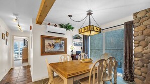 A dining area with a wooden table and chairs, a chandelier, and a stone wall.