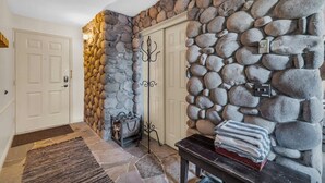 A stone wall interior with a fireplace, a coat rack, and a door.