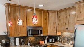 A kitchen with wooden cabinets, granite countertops, stainless steel appliances, and pendant lighting.