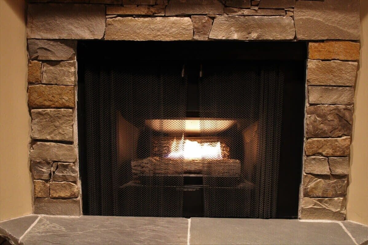 Ein steiner Kamin mit brennendem Feuer, umgeben von Steinwänden.