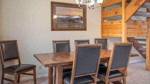 A dining area with a wooden table and chairs, a chandelier, and a staircase. - Charming 2 BDR Getaway w/ Views & Private Hot Tub! (Park City)