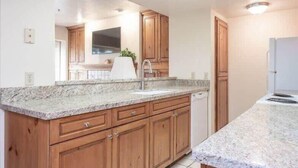 A modern kitchen with granite countertops, wooden cabinets, and a built-in dishwasher. - Charming 2 BDR Getaway w/ Views & Private Hot Tub! (Park City)