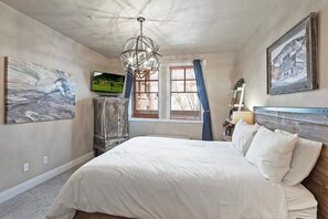 A bedroom with a large bed, a chandelier, a television, and artwork on the walls. - 3BDR Condo Heart of Old Town Walk to Town Lift (Park City)
