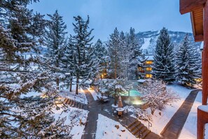 Un'area esterna innevata con piscina, sedie a sdraio e una scalinata che conduce a un edificio.