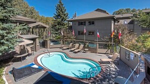 A swimming pool area with lounge chairs, a covered seating area, and flags. - Ski-in/out 2 BDR Condo in the Heart of the Action! (Park City)