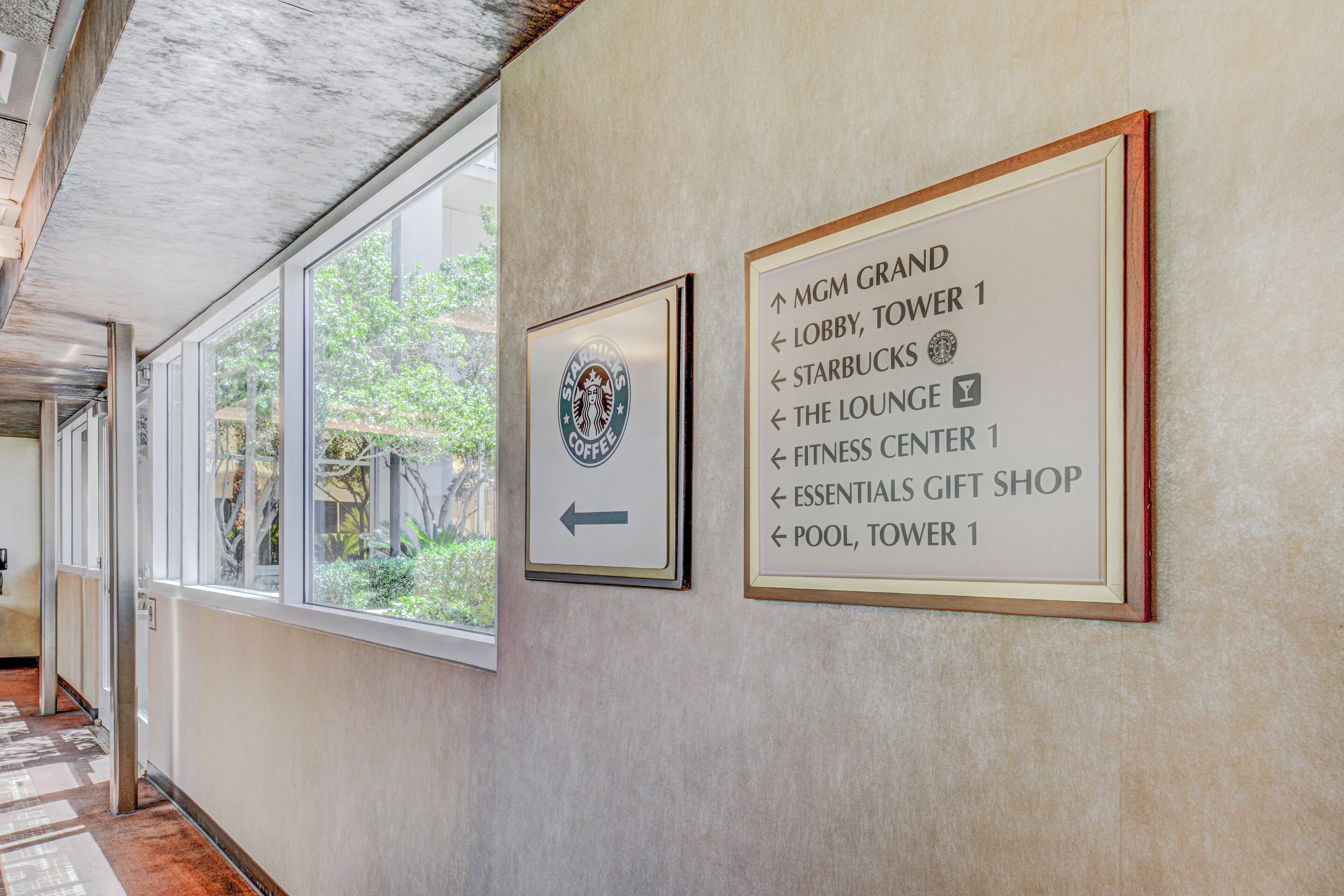A hallway with directional signs to MGM Grand, lobby, tower 1, Starbucks, lounge, fitness center, essentials gift shop, and pool, tower 1.